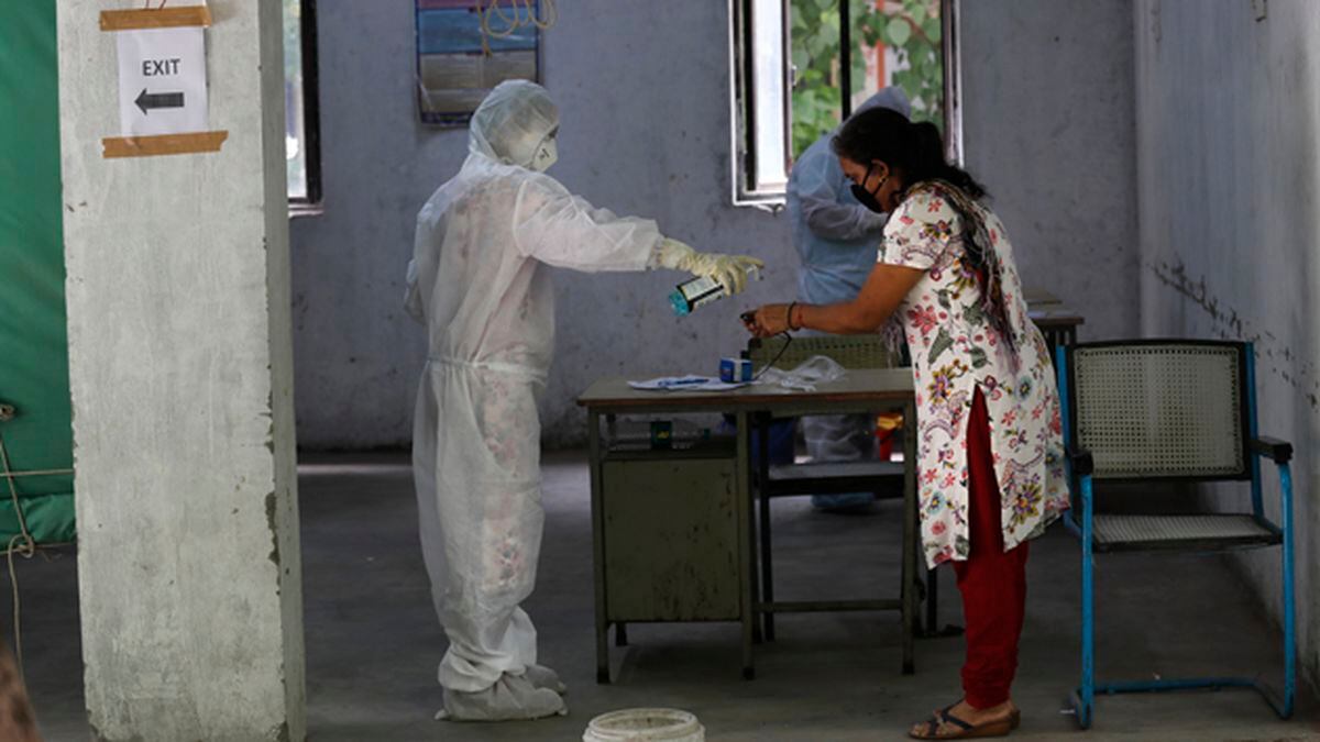 A health worker gives hand sanitizer to a woman after taking her sample for the COVID-19 rapid antigen test in New Delhi, India, on Friday, June 19, 2020. (AP Photo/Manish Swarup)